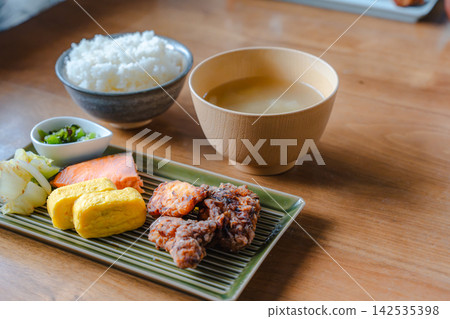 A photo of a Japanese set meal with grilled salmon, omelet, fried chicken, rice, and miso soup on a table. A photo of a Japanese set meal with grilled salmon, omelet, fried chicken, rice, and miso soup on a table. 142535398