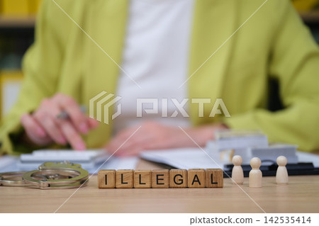 Exploring the meaning of illegal with wooden blocks and legal tools on a desk 142535414