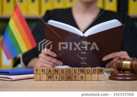 Advocacy for transgender rights through education and legal support; a person reads at a desk with documents and a gavel Advocacy for transgender rights through education and legal support; a person reads at a desk with documents and a gavel 142535508