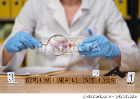 Exploring criminalistics: a forensic expert examines evidence under a magnifying glass Exploring criminalistics: a forensic expert examines evidence under a magnifying glass 142535529