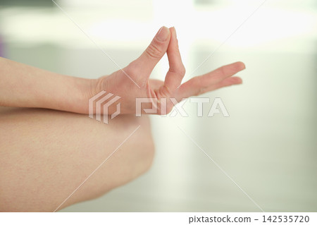Woman shows mindful yoga gesture in comfortable lotus position Woman shows mindful yoga gesture in comfortable lotus position 142535720