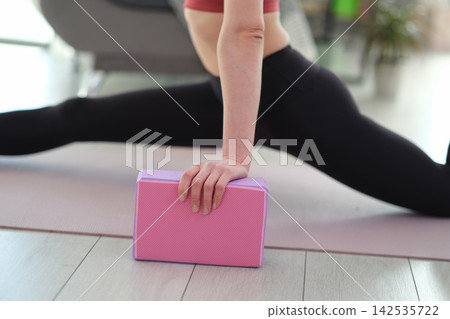 Woman performs flexibility exercise sitting in full front split Woman performs flexibility exercise sitting in full front split 142535722