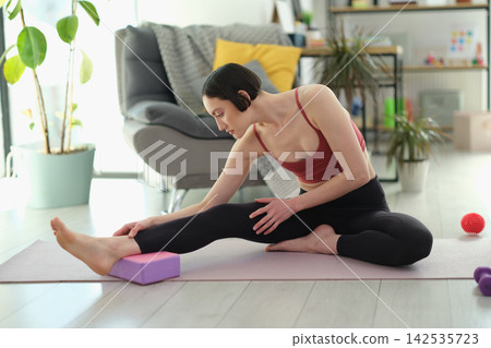 Athlete practices stretching pose using purple exercise block Athlete practices stretching pose using purple exercise block 142535723