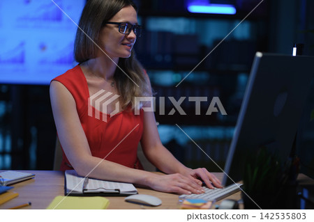 Positive woman employee with glasses types on computer Positive woman employee with glasses types on computer 142535803