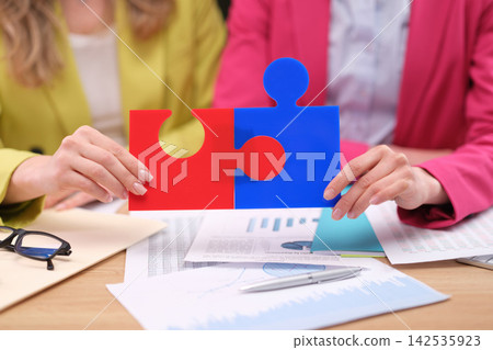 Colleagues carefully fit colorful puzzle fragments together Colleagues carefully fit colorful puzzle fragments together 142535923