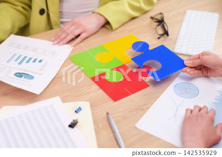Office workers connect colorful puzzle pieces on desk Office workers connect colorful puzzle pieces on desk 142535929