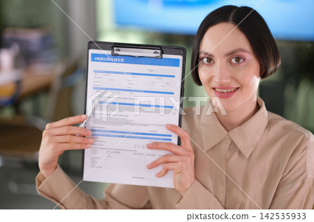 Cheerful woman working as insurance agent holds insurance policy Cheerful woman working as insurance agent holds insurance policy 142535933