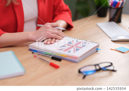 English teacher sits at desk with British-themed notebook English teacher sits at desk with British-themed notebook 142535934