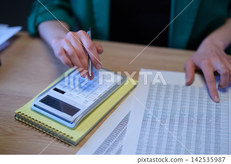 Accountant audits data in spreadsheet and counts on calculator Accountant audits data in spreadsheet and counts on calculator 142535987