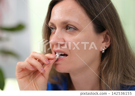 Woman puts mint chewing gum in mouth to freshen mouth closeup Woman puts mint chewing gum in mouth to freshen mouth closeup 142536155