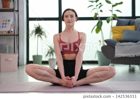 Woman practices butterfly pose during peaceful yoga session Woman practices butterfly pose during peaceful yoga session 142536331