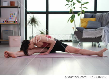 Athlete in workout clothes gently bends torso toward legs 142536332