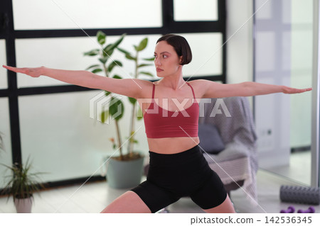 Athletic woman performs gentle stretching yoga exercise Athletic woman performs gentle stretching yoga exercise 142536345
