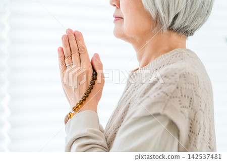 一位年長的婦女每天都會在家裡的祭壇前祈禱,祭拜祖先。 一位年長的婦女每天都會在家裡的祭壇前祈禱,祭拜祖先。 142537481