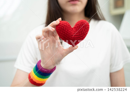 Asian LGBT woman holding heart rainbow flag. Asian LGBT woman holding heart rainbow flag. 142538224