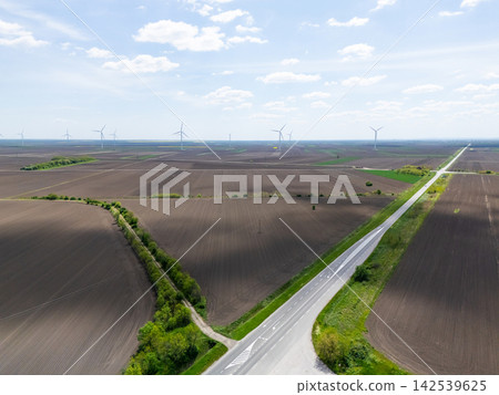 Aerial view of a road passing through farm fields with wind turbines Aerial view of a road passing through farm fields with wind turbines 142539625