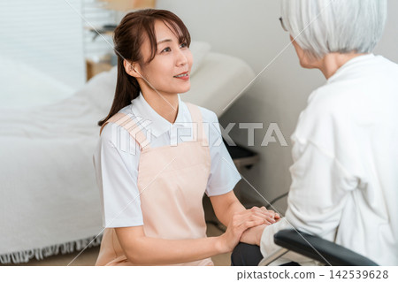 一位女護理員正在照顧一位坐在輪椅上的老婦人。這是一個充滿微笑、溝通順暢的照護環境。 142539628