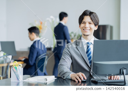 工作在辦公室的一個年輕商人 工作在辦公室的一個年輕商人 142540016