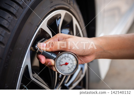 Close-Up Of Hand holding pressure gauge for car tyre pressure measurement Close-Up Of Hand holding pressure gauge for car tyre pressure measurement 142540132