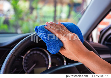 Hand with microfiber cloth cleaning Interior and steering wheel modern car. Hand with microfiber cloth cleaning Interior and steering wheel modern car. 142540133