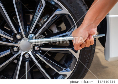 Hands disassembling a modern car wheel steel rim with a lug wrench for change wheel or repair and maintenance Hands disassembling a modern car wheel steel rim with a lug wrench for change wheel or repair and maintenance 142540134