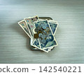 Banknotes and yen coins of various denominations are placed in a change tray on a wooden floor. 142540221