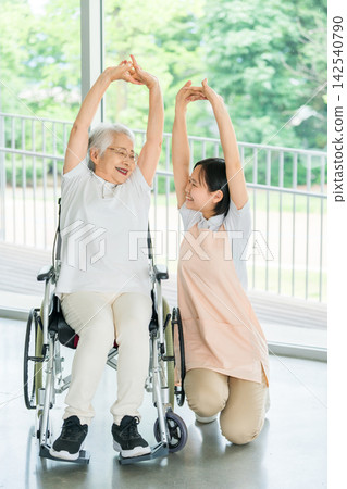 復健場景：一名護理人員正在為一位坐在輪椅上的老年婦女做伸展運動。 142540790