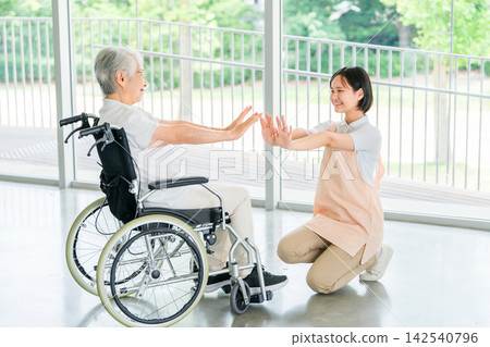 功能性訓練:一位坐在輪椅上的老年婦女和她的護理人員面帶微笑地進行鍛鍊。 功能性訓練:一位坐在輪椅上的老年婦女和她的護理人員面帶微笑地進行鍛鍊。 142540796