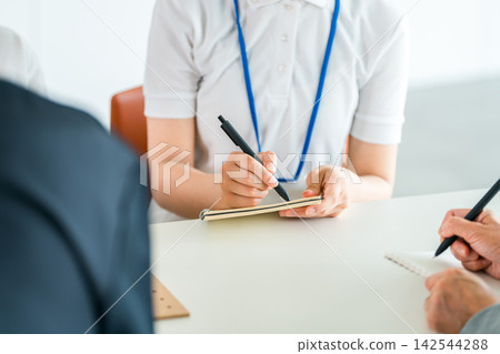 A woman's hands taking notes while listening to a presentation at a training session or study group. A woman's hands taking notes while listening to a presentation at a training session or study group. 142544288