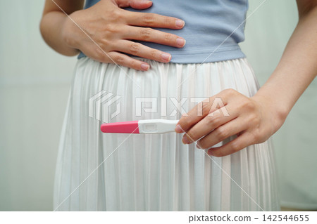 Asian holding pregnancy test for female of ovulation day, fetus, maternity, childbirth, birth control. Asian holding pregnancy test for female of ovulation day, fetus, maternity, childbirth, birth control. 142544655