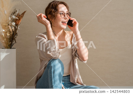 A woman wearing glasses is happily talking on her smartphone. A woman wearing glasses is happily talking on her smartphone. 142544803