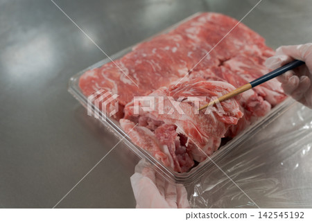 一雙女人的手將大量的肉分成小份。 一雙女人的手將大量的肉分成小份。 142545192