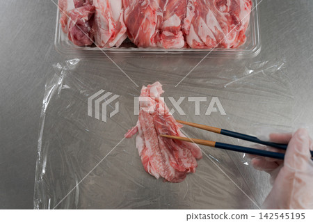 一雙女人的手將大量的肉分成小份。 一雙女人的手將大量的肉分成小份。 142545195