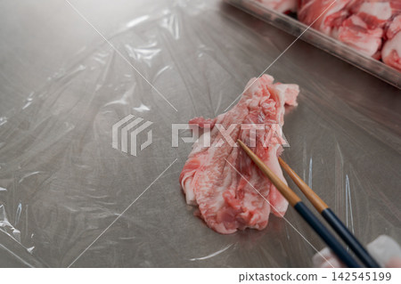 一雙女人的手將大量的肉分成小份。 一雙女人的手將大量的肉分成小份。 142545199