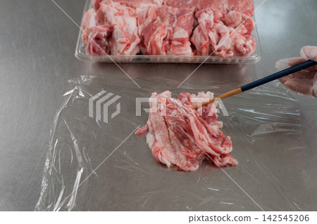 一雙女人的手將大量的肉分成小份。 一雙女人的手將大量的肉分成小份。 142545206