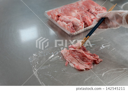 一雙女人的手將大量的肉分成小份。 一雙女人的手將大量的肉分成小份。 142545211