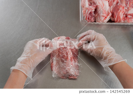 一雙女人的手將大量的肉分成小份。 一雙女人的手將大量的肉分成小份。 142545269