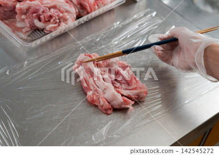 一雙女人的手將大量的肉分成小份。 142545272