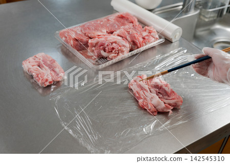 一雙女人的手將大量的肉分成小份。 一雙女人的手將大量的肉分成小份。 142545310