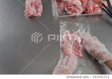 一雙女人的手將大量的肉分成小份。 142545313