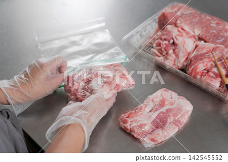 一雙女人的手將大量的豬肉分成小份量。 一雙女人的手將大量的豬肉分成小份量。 142545552