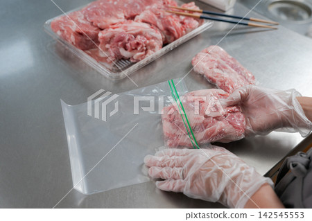 一雙女人的手將大量的豬肉分成小份量。 一雙女人的手將大量的豬肉分成小份量。 142545553