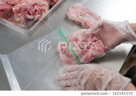 一雙女人的手將大量的豬肉分成小份量。 一雙女人的手將大量的豬肉分成小份量。 142545555