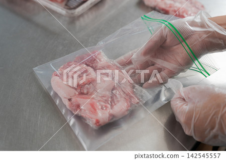 一雙女人的手將大量的豬肉分成小份量。 一雙女人的手將大量的豬肉分成小份量。 142545557