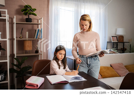 Mother helping daughter with homework at home 142547418