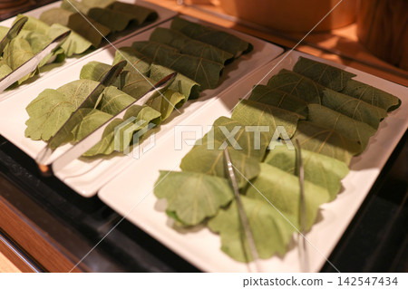 飯店的甜點自助餐檯上擺放著綠色的柏餅。這些寓意吉祥的日式甜點是為男孩節準備的,整齊地擺放在方形盤子裡。 飯店的甜點自助餐檯上擺放著綠色的柏餅。這些寓意吉祥的日式甜點是為男孩節準備的,整齊地擺放在方形盤子裡。 142547434