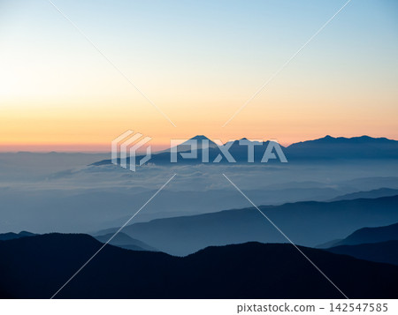 九月下旬,從北穗高山遠眺日出,可以看到漸變的天空、富士山和雄偉的南阿爾卑斯山脈的輪廓。 九月下旬,從北穗高山遠眺日出,可以看到漸變的天空、富士山和雄偉的南阿爾卑斯山脈的輪廓。 142547585