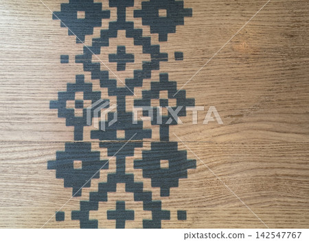 Traditional geometric ornament printed on natural wooden board surface with detailed grain texture Traditional geometric ornament printed on natural wooden board surface with detailed grain texture 142547767