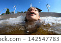 A young girl enjoying water jets in a swimming pool 142547783