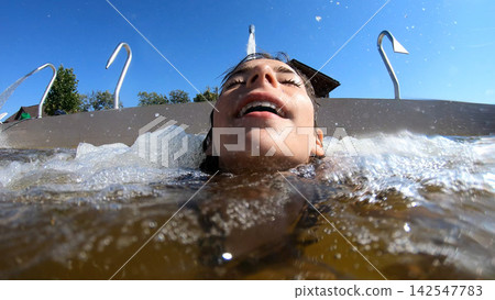 A young girl enjoying water jets in a swimming pool A young girl enjoying water jets in a swimming pool 142547783
